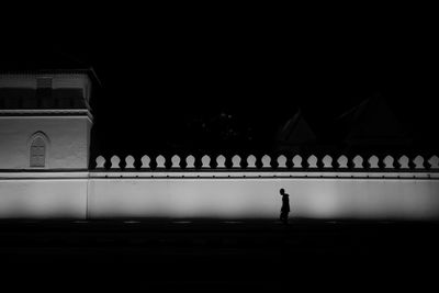 Silhouette man standing against illuminated building at night