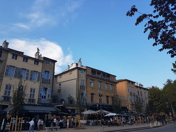 People on buildings in city against blue sky