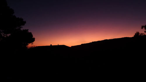 Scenic view of silhouette mountains against clear sky during sunset