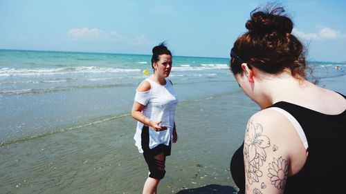 Women standing on beach against sea