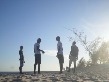 People standing on beach against clear sky