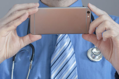 Midsection of doctor using phone in hospital