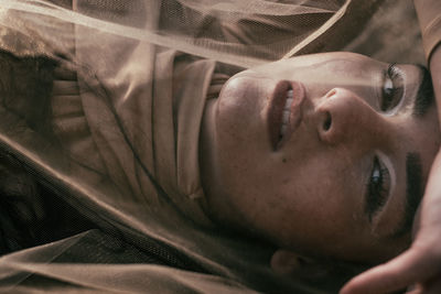 Close-up portrait of young woman on bed