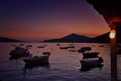 Boats in sea at sunset