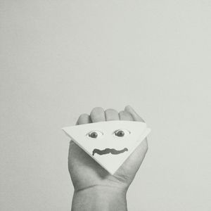 Close-up of hand holding paper over white background