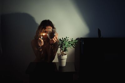 Young woman holding vase with water in darkroom at home