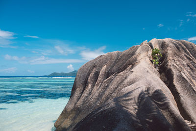 Rock formation by sea against blue sky