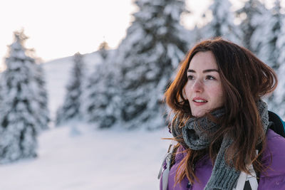 Woman having fun while hiking in the snow during winter, at sunset time.