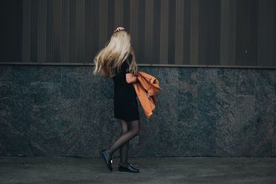 Woman walking on street by building