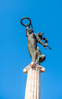 Low angle view of angel statue against blue sky