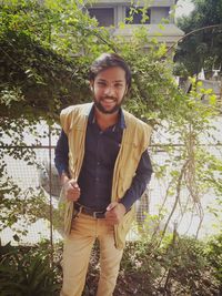 Portrait of young man standing against plants
