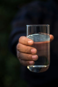 Cropped hand of man holding water in glass