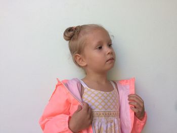 Close-up of girl standing against white wall