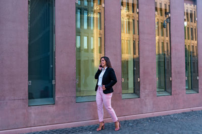 Full length of woman standing against building in city