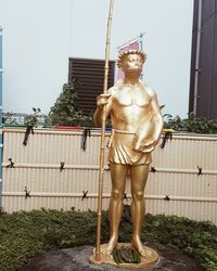 Statue of man standing by plants against building