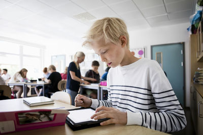 Boy using tablet pc at desk in classroom