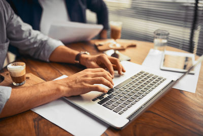 Midsection of man using laptop at office