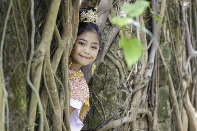 Portrait of smiling girl on tree trunk