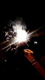 Close-up of hand holding illuminated firework display at night