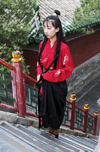 Full length of woman standing against red wall