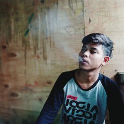 Portrait of young man looking away against wall