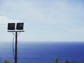 Street light by sea against sky