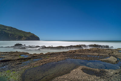 Scenic view of beach against clear blue sky