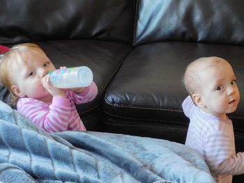 High angle portrait of siblings standing by sofa at home