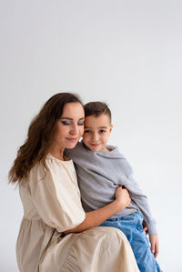 Portrait of young woman standing against white background