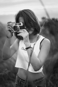 Young woman photographing on field