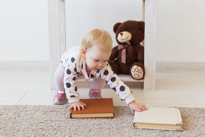 Cute girl looking at toy while sitting on floor at home