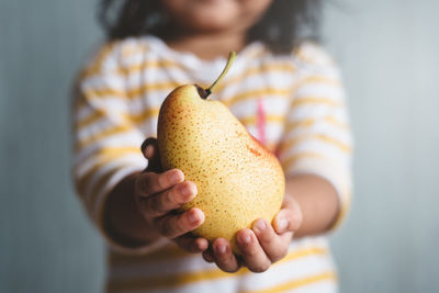 Midsection of girl holding pear
