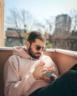 Midsection of man holding sunglasses while sitting outdoors