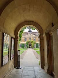 View from archway to a path leading to the stone facade of a magnificent historical building. 