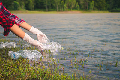 Midsection of woman holding plants in lake