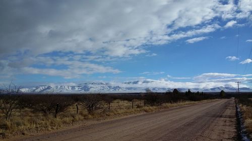 Country road against cloudy sky