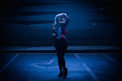 Full length portrait of woman standing against wall