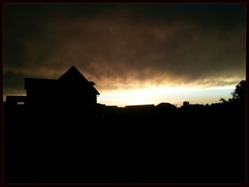 Silhouette of buildings against cloudy sky