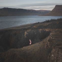 Woman standing on mountain by sea against sky