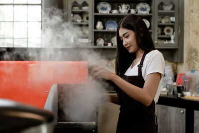 Young woman holding ice cream standing in kitchen