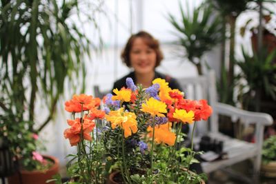 Close-up of colorful flowers against mature woman in shop