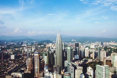 Aerial view of cityscape against cloudy sky