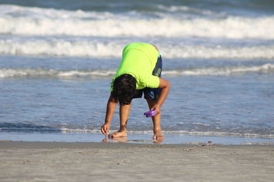 Boy bending on shore at beach