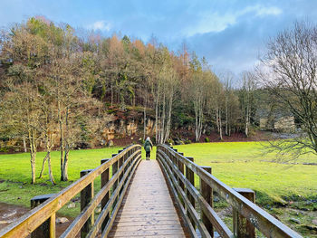 Woman walking across a wooden bridge