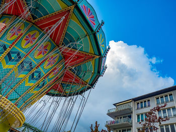 Low angle view of merry-go-round against buildings in city