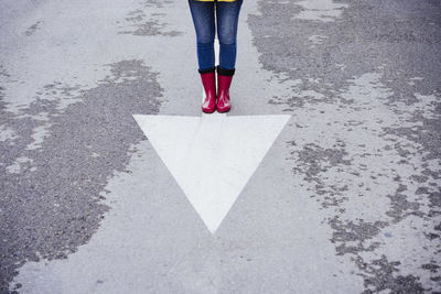 Woman standing on arrow symbol on road