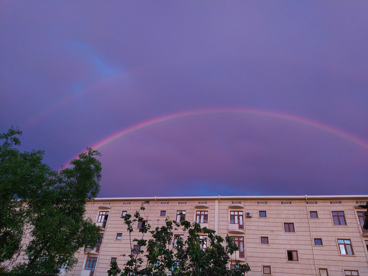 rainbow, architecture, tree, sky, building exterior, plant, built structure, nature, beauty in nature, double rainbow, cloud, multi colored, building, city, no people, scenics - nature, low angle view, outdoors, tranquility, environment, natural phenomenon, residential district, storm, day, house, idyllic