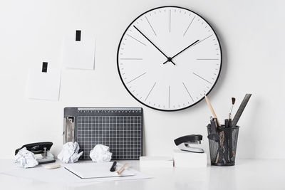 Clock on table against white wall