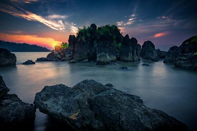 Rocks on sea against sky during sunset