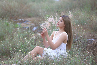 Side view of woman sitting on field